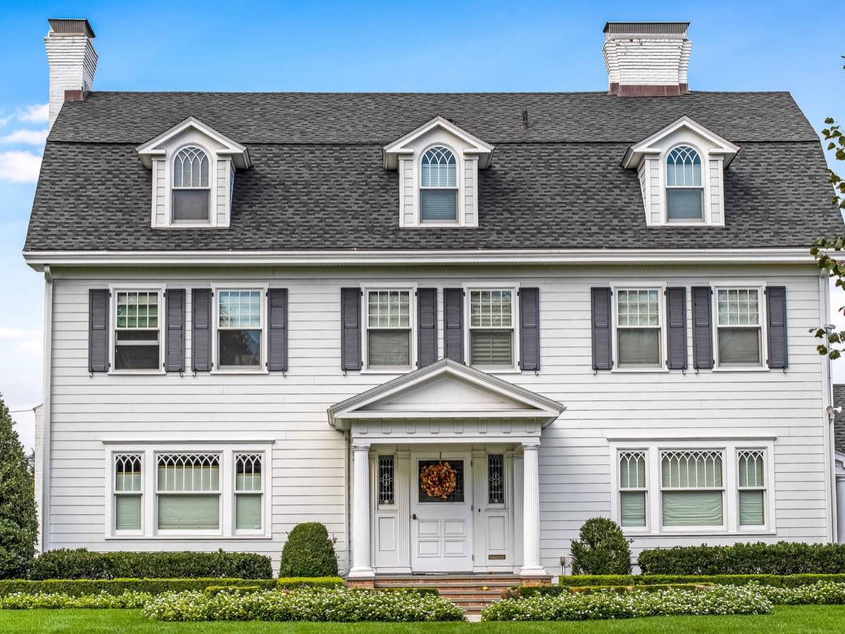 A white colonial home with black shutters, the cover of the Home Buying Guide